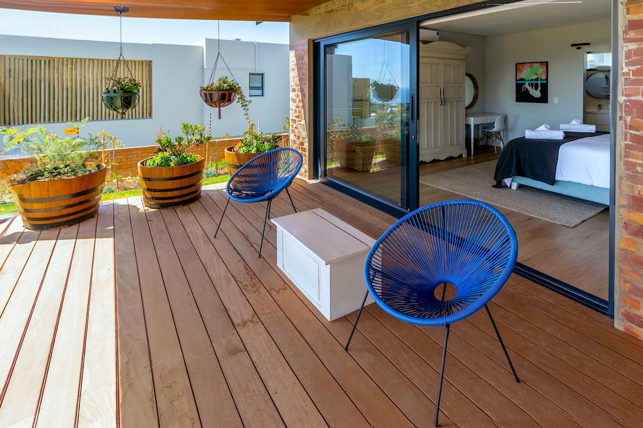 Bedroom balcony with blue Acapulco chairs and wooden planters