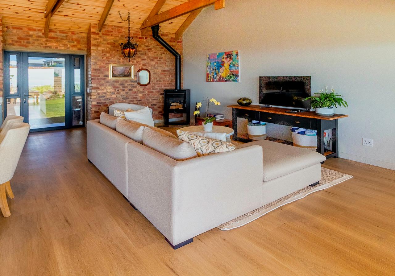 Cozy living room with exposed brick wall, wood stove, and vaulted ceiling